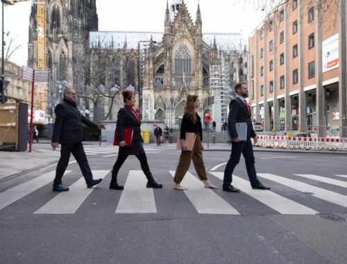Die Mitglieder der FRAKTION im Rat der Stadt Köln überqueren einen Zebrastreifen vor dem Dom