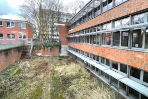 Ehemalige André-Thomkins-Schule in Köln-Mülheim. Außenansicht eines leerstehenden Schulgebäudes mit verwildertem Innenhof.